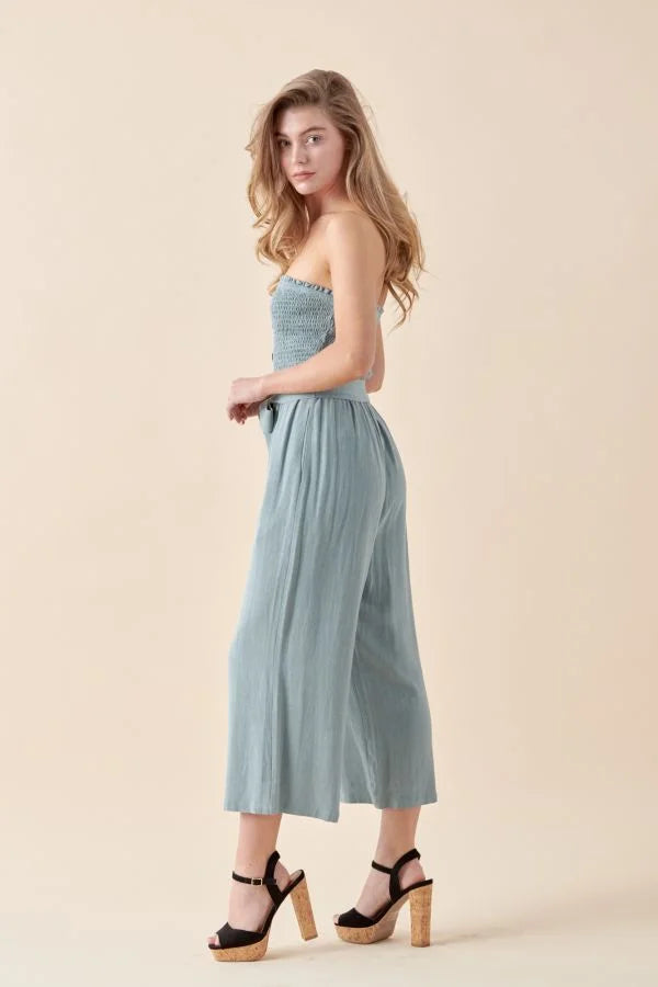 Woman in a soft linen smocked tube jumpsuit and platform sandals, stylish summer fashion