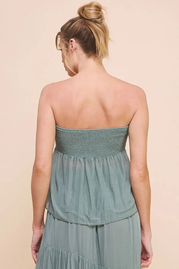 Woman in a strapless teal crinkled woven boho dress with a bun, viewed from behind