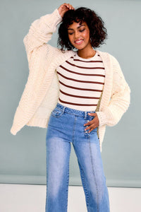 Woman in a striped top and oversized knit sweater cardigan from Shop Daisy, showcasing women’s boho chic clothing