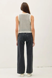 Woman wearing a chunky knit striped sweater tank paired with wide-leg jeans