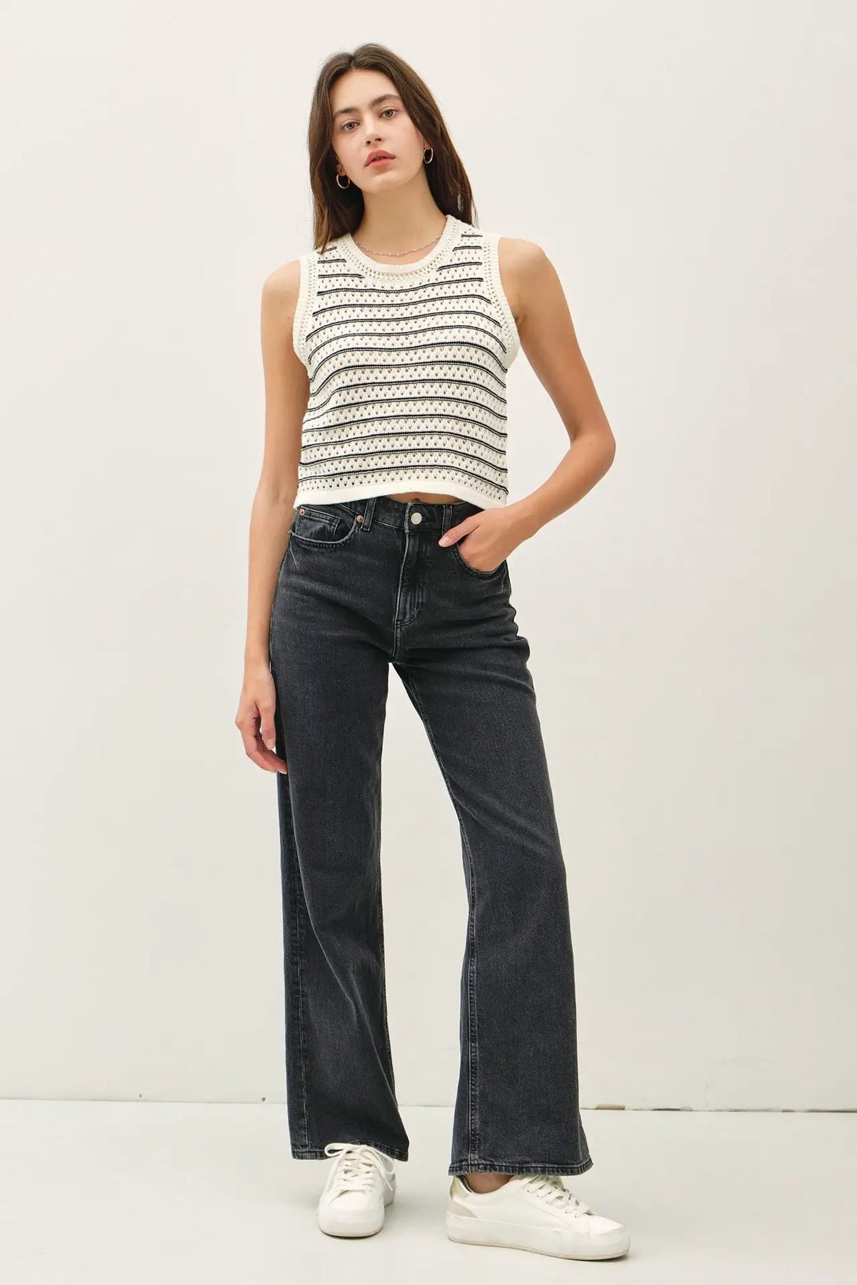 Woman wearing a chunky knit striped sweater tank with dark wash jeans