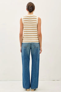 Woman wearing a chunky knit striped sweater tank with contrast accents and blue jeans