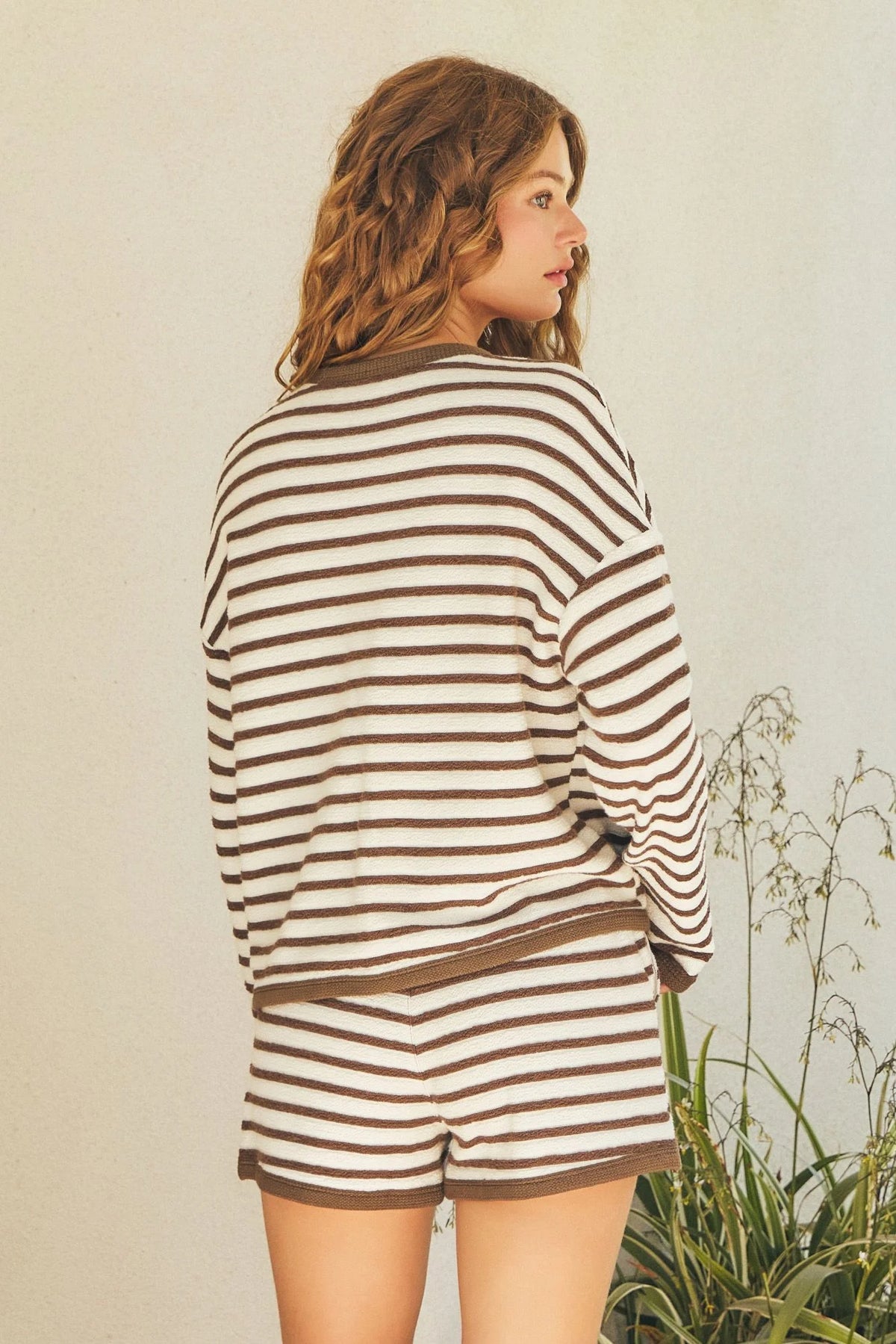 Woman in striped long-sleeved top and shorts from Shop Daisy’s women’s boho chic clothing