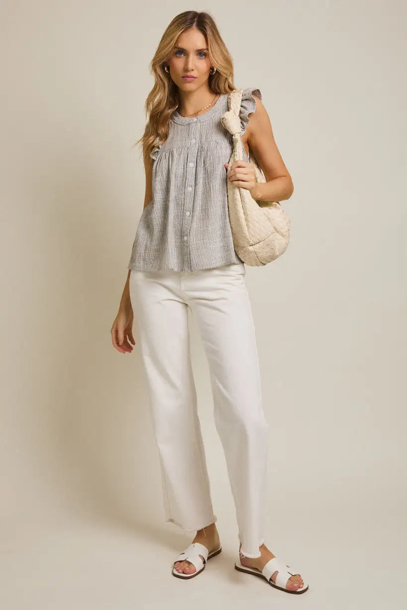 Woman wearing a round neck button ruffle sleeve stripe top with white pants