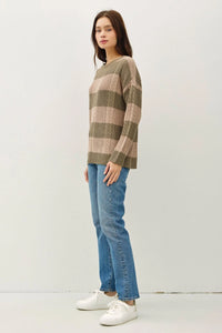 Woman in striped cable knit crew neck sweater paired with blue jeans, showcasing boho style