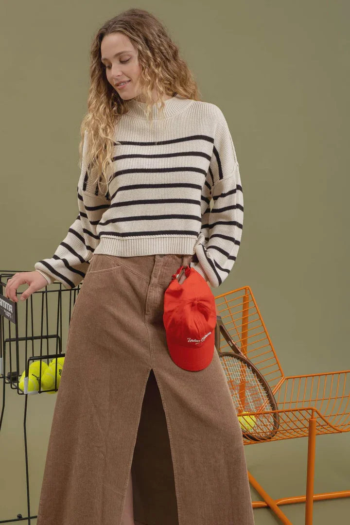 Woman in striped mock neck ribbed sweater and brown skirt with a shopping basket