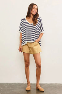 Woman wearing v-neck oversized stripe sweater top paired with tan shorts