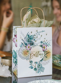 Woman sitting at a table with Daisy Lane Happy Birthday Darling gift bag