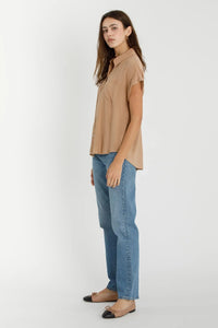 Woman wearing a tan blouse and blue jeans showcasing the SOLID SHORT SLEEVE BUTTON DOWN SHIRT in women’s boho chic clothing from Shop Daisy
