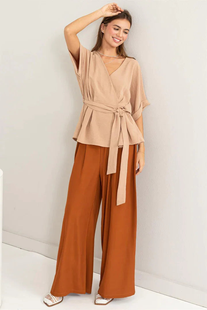 Woman in a tan top showcasing high waist wide leg pants in a stylish setting