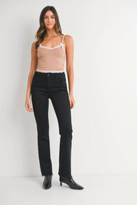 Woman wearing tan camisole and black pants with mid rise flare denim jeans