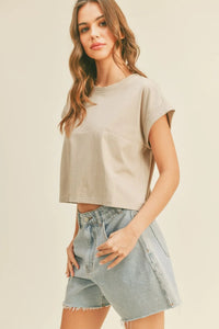 Woman wearing a tan round neck cuffed sleeve top with light wash denim shorts