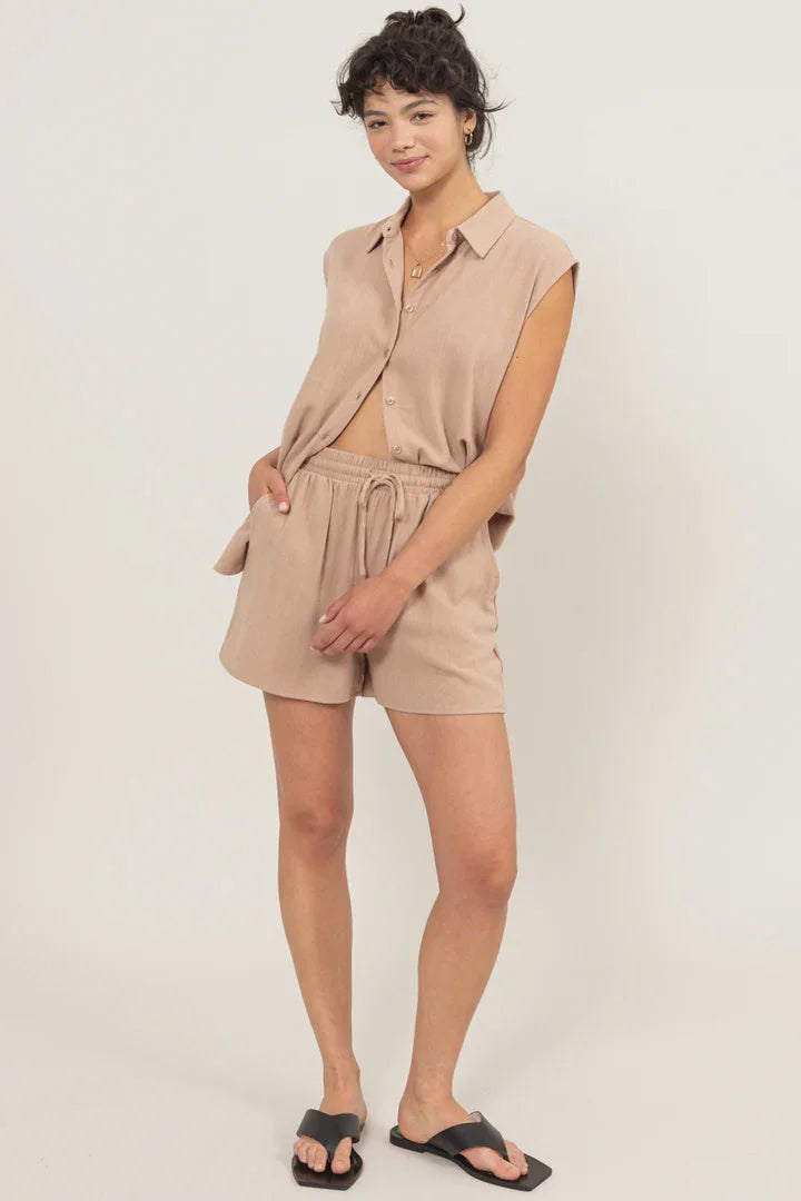 Woman in a tan linen shirt and shorts set, showcasing a boho, flowy style