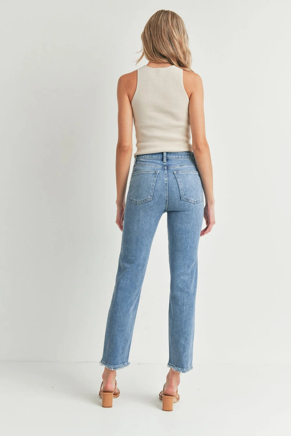 Woman in tank top and jeans showcasing Hem Bust Jeans against a white background