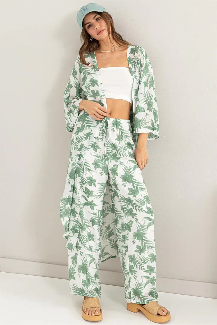 Woman in a boho floral duster pants set with a white crop top and wide-leg design