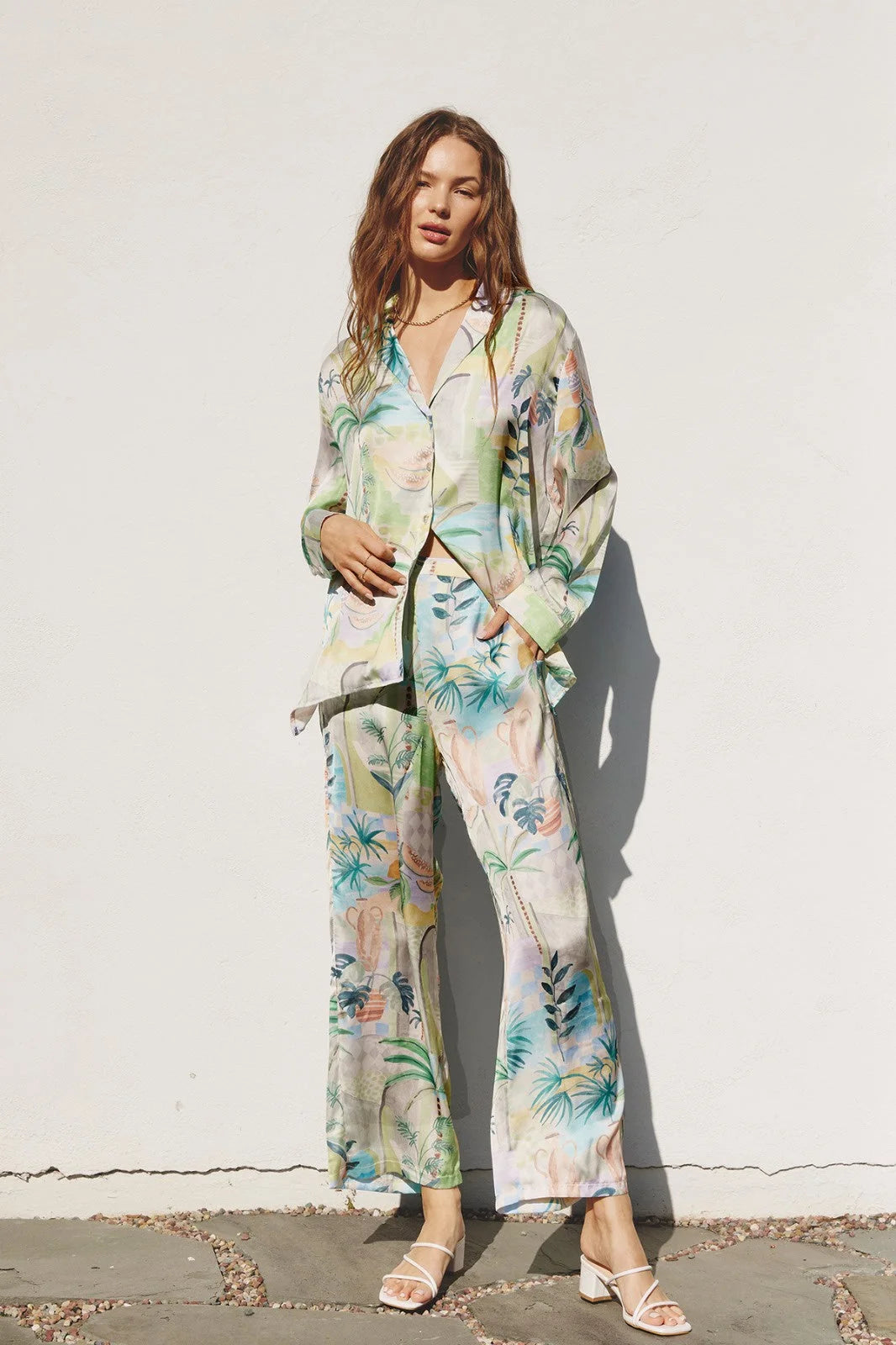 A woman in a boho tropical print shirt and flowy matching pajama pants set