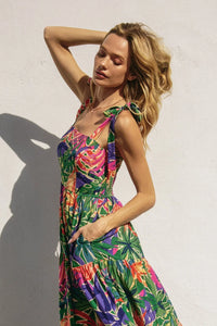 Woman wearing vibrant tropical smocked tie shoulder maxi dress with pockets