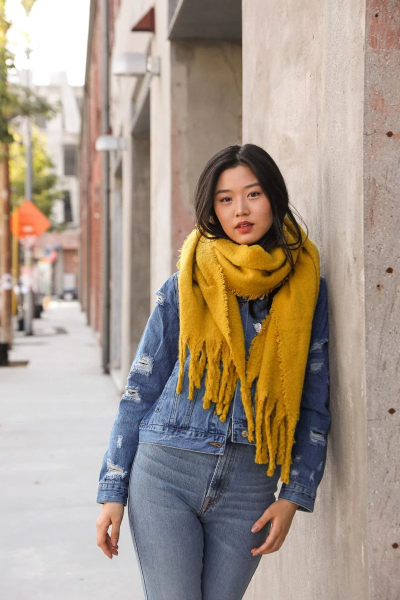 Woman in denim jacket and mustard yellow scarf styled with Cozy Mohair Tassel trim