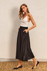 Woman in a white top and black HEAVEN SENT flared maxi skirt, showcasing elegant style