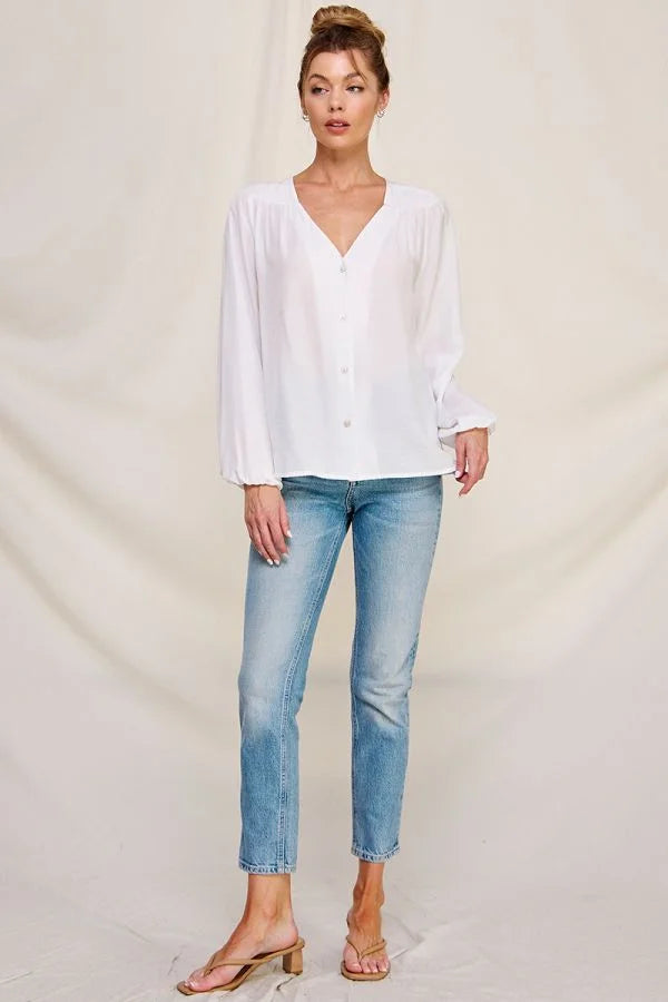 Woman in a white flowy button front shirt and jeans showcasing boho style