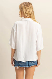 Woman wearing a white linen blouse and denim shorts showcasing women’s boho chic clothing from Shop Daisy