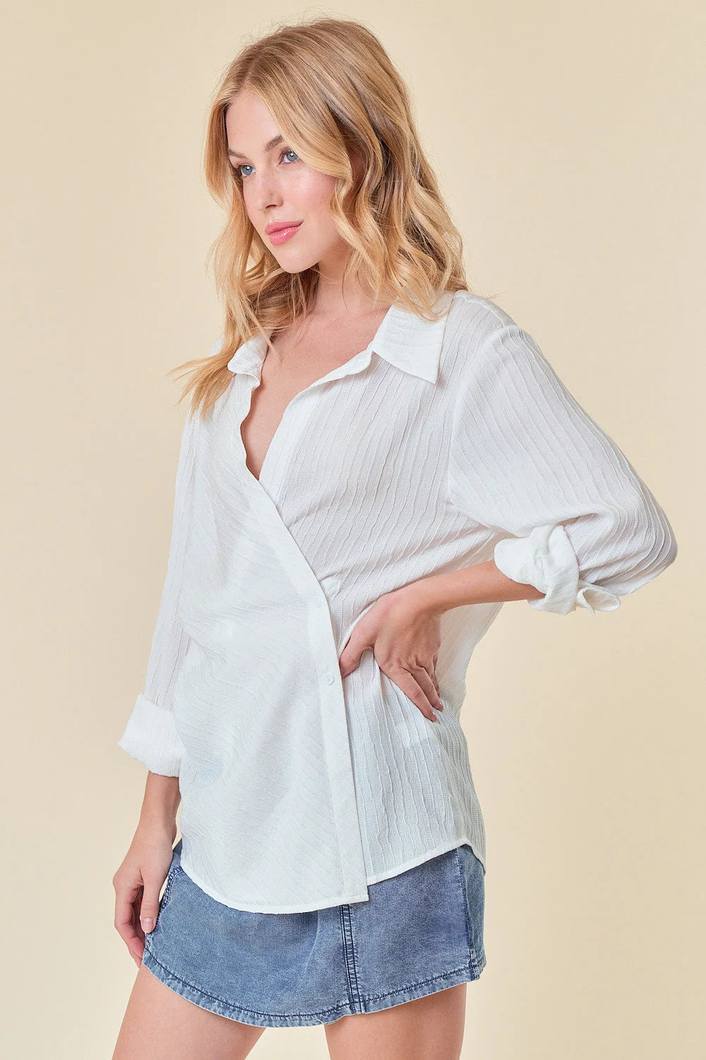 Woman in a white blouse and denim shorts showcasing the Textured Point Collar Wrap Top