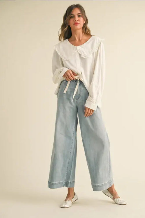 Woman in a white blouse wearing WSHD denim pants with wide legs for a stylish look