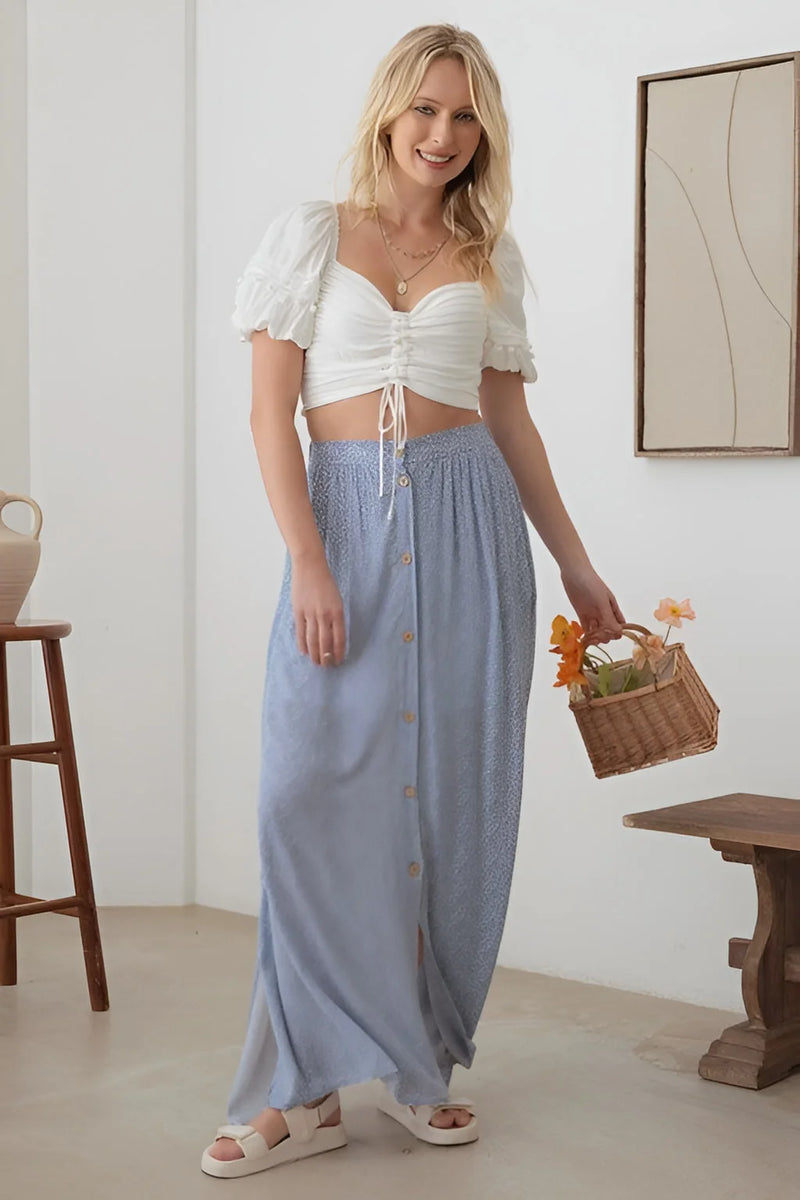 Woman in a white top and blue skirt showcasing the Boho Front Button Floral Maxi Skirt