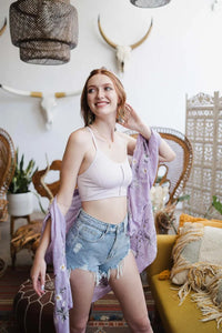 Woman in white top and blue denim shorts wearing Seamless Longline Pullover Boho Bralette