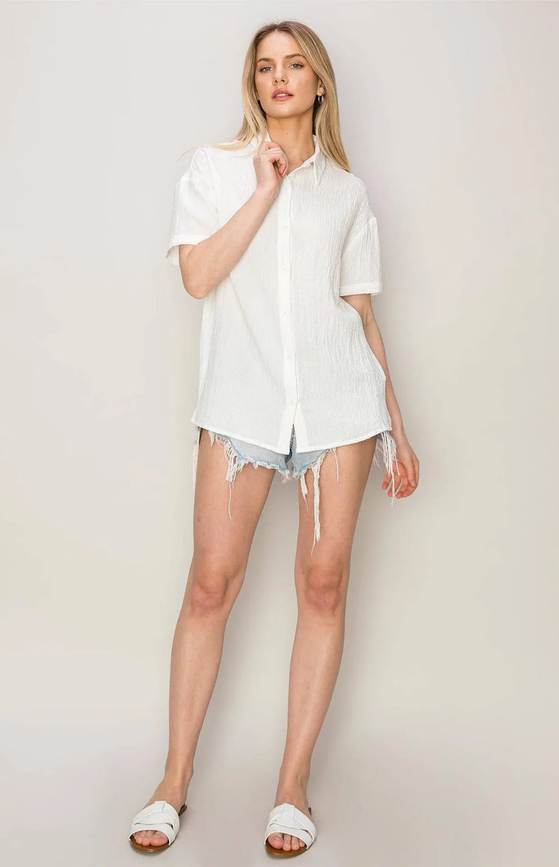 Woman in a flowy white button-up shirt and denim shorts, perfect for a boho free spirit