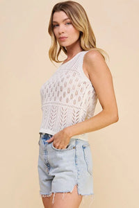 Woman in a light pointelle sweater tank with denim shorts, showcasing summer style