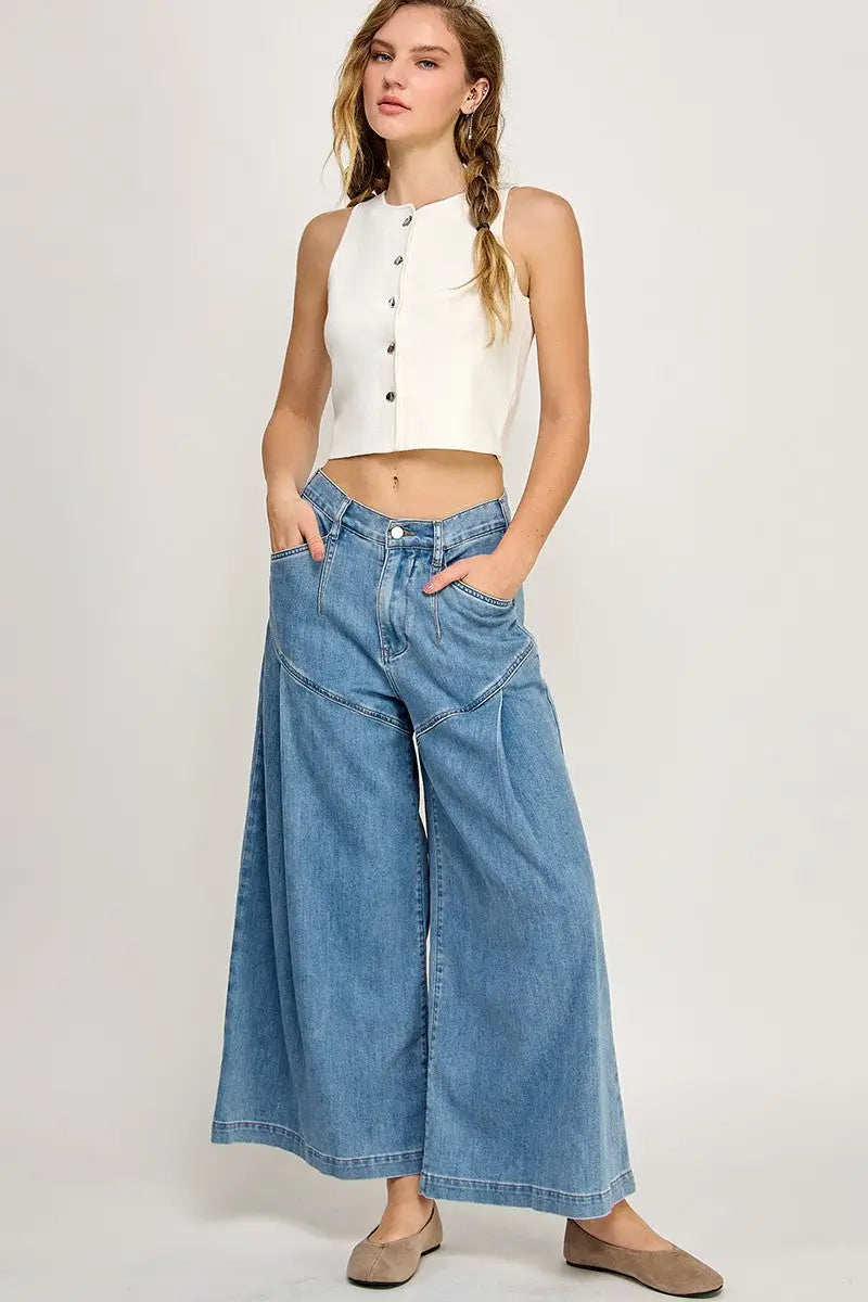 Woman in a white crop top and wide-leg flare jeans from Shop Daisy’s boho chic collection