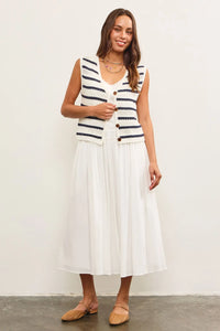 Woman in a white dress wearing a striped button closure sleeveless vest from Shop Daisy