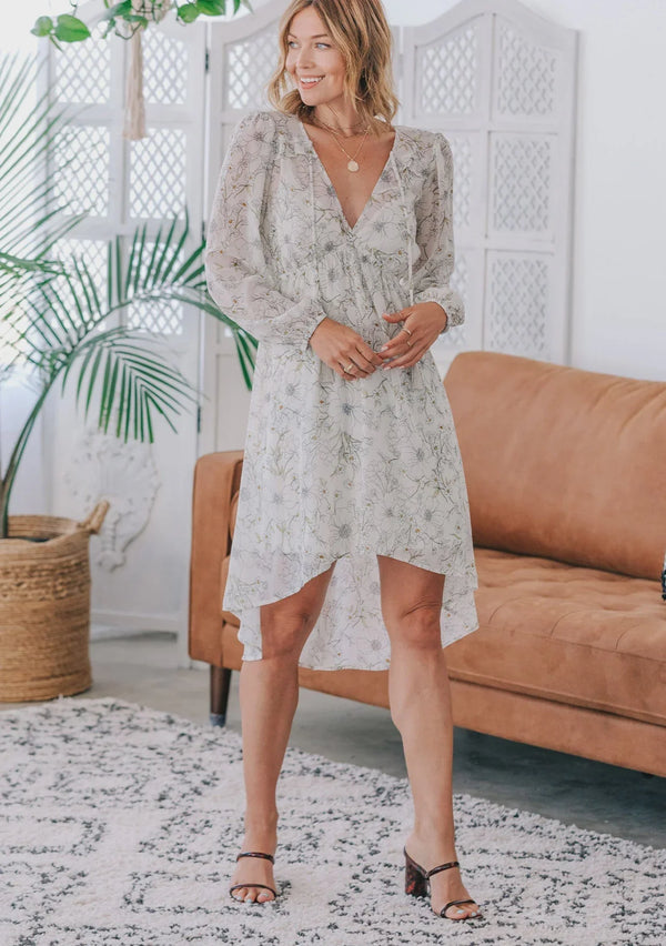 Woman wearing floral print long sleeve midi dress with high-low hem and brown block heels