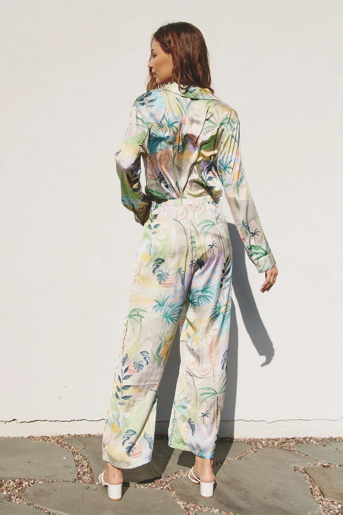 Woman in a flowy white and green tropical print shirt and pants set for a boho style