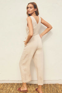 Woman in a white BUTTON DOWN SASH BELT JUMPSUIT featuring v-neck button closures