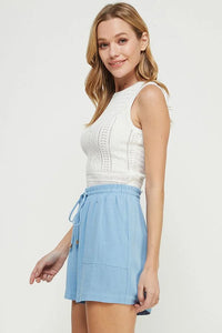 Woman wearing a white fine gauge tank top with mixed pointelle detail and blue shorts