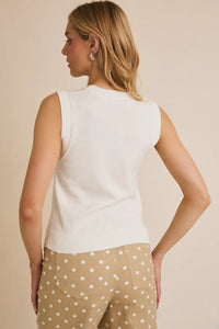 Woman wearing a white knit vest and polka dot pants showcasing a sleeveless USA flag sweater tank