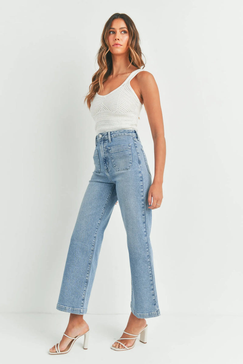 Woman in white knit top and light blue wide leg denim jeans with patch pockets
