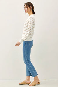 Woman wearing lightweight striped long sleeve sweater with blue jeans and light brown heels