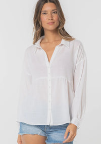 Woman modeling bohemian long sleeve tiered button front top with distressed denim shorts