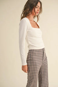 Woman in a white long-sleeved top and plaid pants from Shop Daisy’s women’s boho chic clothing