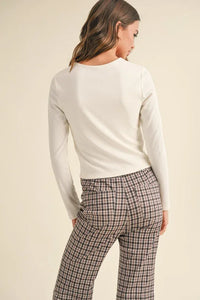 Woman in a white long-sleeved top and plaid pants, showcasing womens boho clothes