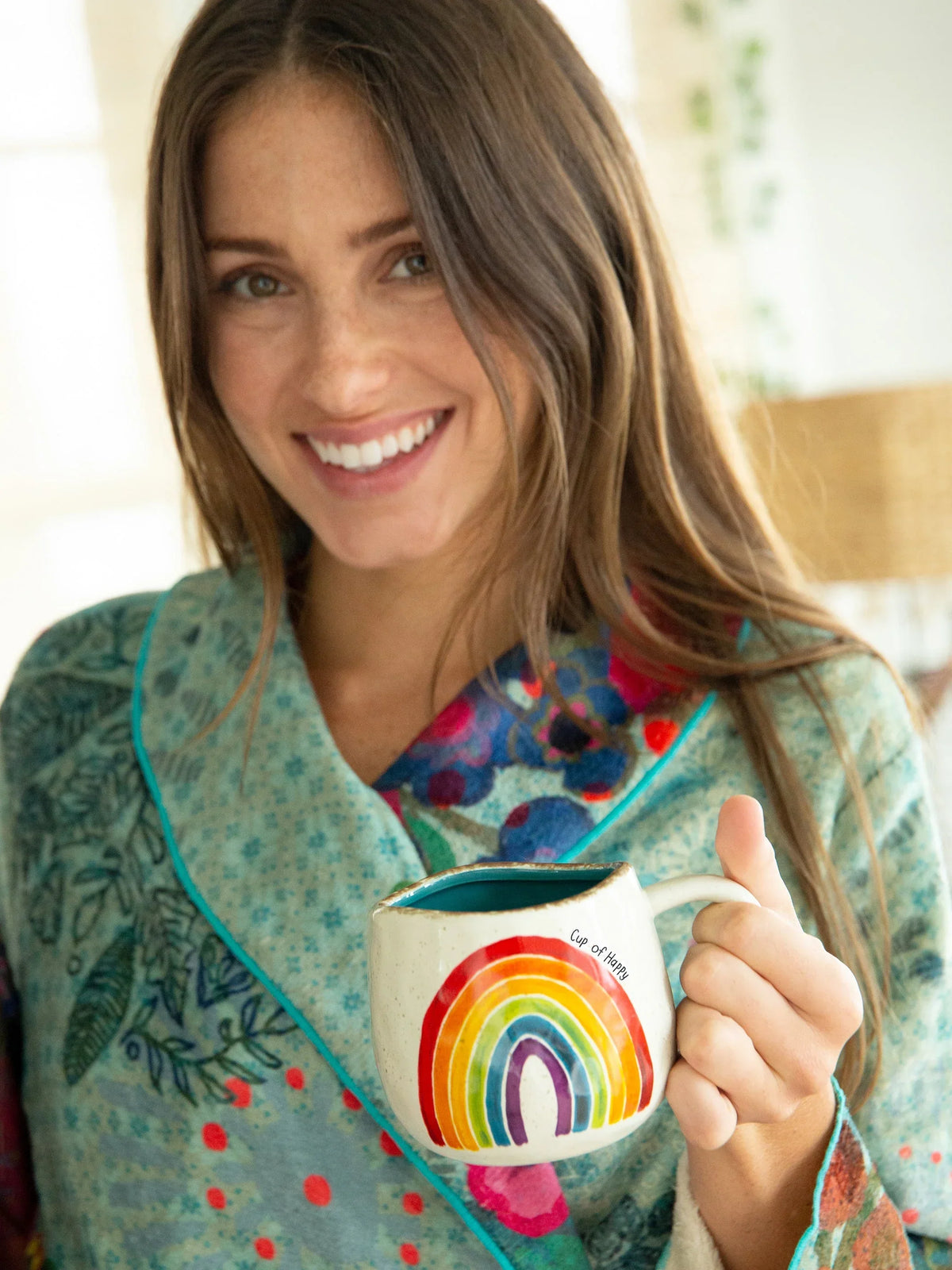 Smiling woman with boho style holding a rainbow mug from ARTISAN RAINBOW COFFEE MUG