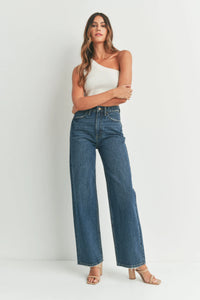 Woman in a stylish white one-shoulder top paired with high waisted skater jeans