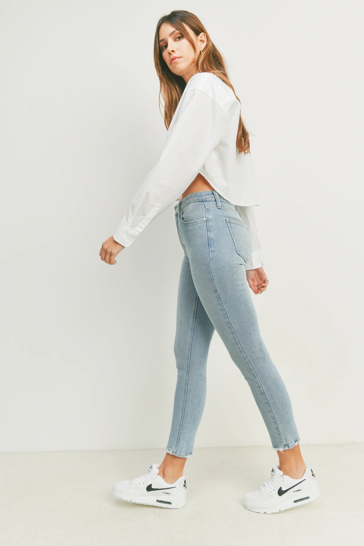 Woman in a white shirt and jeans wearing THE HR Essential Skinny Denim outfit