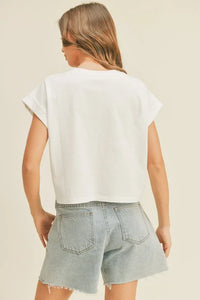 Woman in round neck cuffed sleeve top and denim shorts, viewed from behind