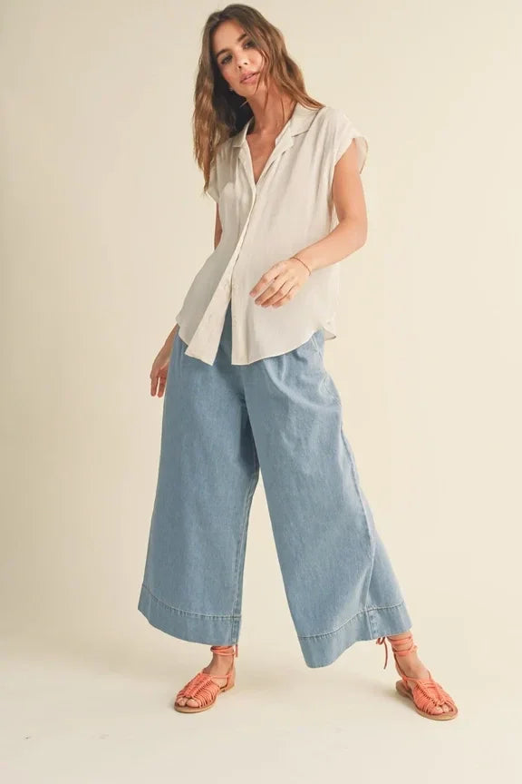 Woman in white cap sleeve shirt and light blue wide-leg pants for stylish summer look