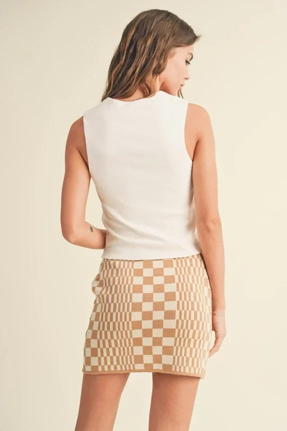 Woman in a white mini ribbed squared neck knitted top and checkered tan skirt