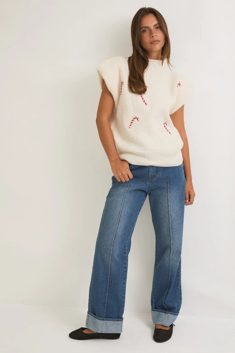 Woman in a white mock neck power shoulder sweater and wide-leg blue jeans